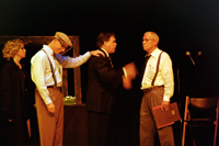 A man putting his hand on the shoulder of a man in a suit talking with a man with a moustache, while a woman looks
        on