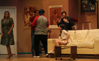 A woman in a green dress pauses as a man in an Avengers T-shirt, a man in a Buccaneers T-shirt, a young woman sitting on a couch, and
       a man in a suit argue